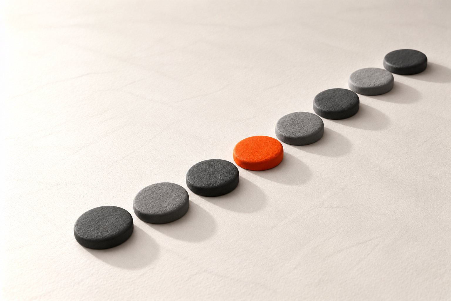 A curved row of grey clay stepping stones with one orange stone partway along